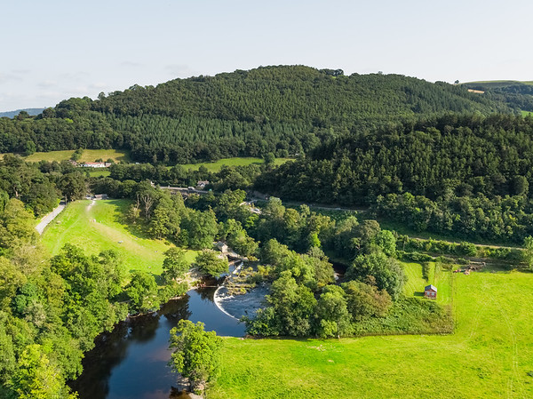 Mae’r afon Dyfrdwy a’r bryniau a choetiroedd | The River Dee and wooded hillsides